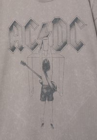 Tricou gri cu logo-ul AC/DC, având o ilustrație grafică a unei persoane care ține un pahar deasupra capului, chitară atârnată de umăr.