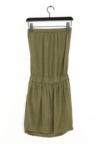 Olivgrünes, ärmelloses Kleid mit elastischem Bund und gerafftem Rock. Hergestellt aus weichem, glattem Stoff, hängt an einem schwarzen Kunststoffhaken.