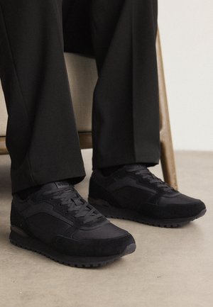 Sneakers neri caratterizzati da un mix di suede testurizzato e mesh liscia, con una silhouette bassa e una resistente suola in gomma.