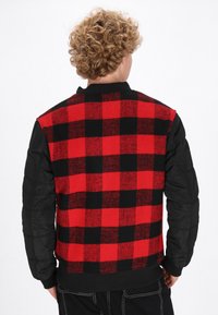 Zwart-rood geblokte jas met een gebreide achterkant en doorgestikte zwarte mouwen, geribbelde kraag en manchetten, met een ontspannen pasvorm.