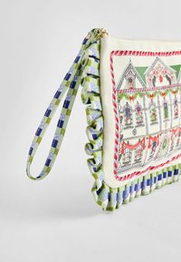 Audinių rankinė su spalvingu pastato dizainu, žalia ir mėlyna kvadratinė juosta bei banguota kraštinė su sudėtingais raštais.