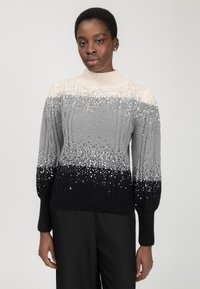 Maglione lavorato a maglia grigio, nero e crema con paillettes, caratterizzato da un collo alto e un design a trecce; maniche lunghe testurizzate con polsini a costine.