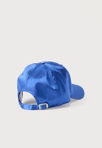 Μπλε σατέν καπέλο μπέιζμπολ με στρογγυλεμένο στέμμα, ανάγλυφη ραφή και ρυθμιζόμενο πίσω λουράκι με μεταλλικό κουμπί. Λείο υλικό και γυαλιστερό φινίρισμα.