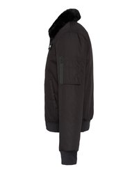 Czarna kurtka bomberka z prążkowanymi mankietami, zamykana kieszonką na rękawie oraz czarnym futrem syntetycznym na kołnierzu, pokazana z lewej strony.