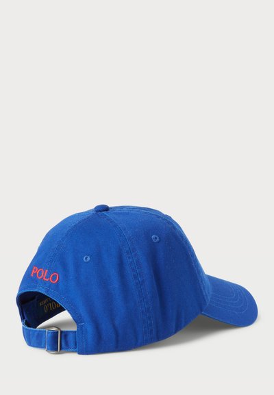 Casquette de baseball en coton bleu avec une visière courbée, une sangle ajustable et une broderie rouge "POLO" à l'arrière. La texture semble douce et durable.