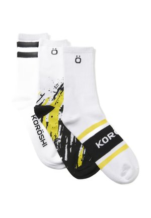 Tres pares de calcetines: uno con un estampado gráfico negro y amarillo, uno blanco con rayas negras y uno completamente blanco con logo.
