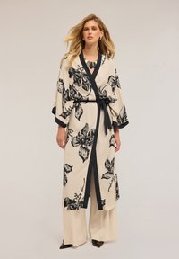 Kimono s květinovým vzorem v béžové barvě s černými akcenty. Obsahuje opasek na zavázání, široké rukávy a hluboký výstřih do V. Nosené přes béžové široké kalhoty.