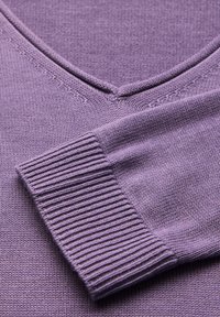 Lila stickad tröja med V-hals, ribbade muddar och fin textur. Har jämn sömning och en mjuk finish.