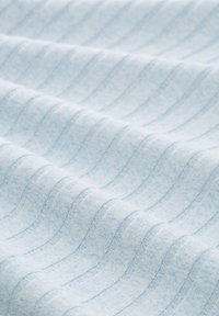 Helles blaues Gewebe mit einem subtilen Wellenmuster und einer weichen, strukturierten Oberfläche; zeichnet sich durch dünne, vertikale Streifen in etwas dunklerem Blau aus.