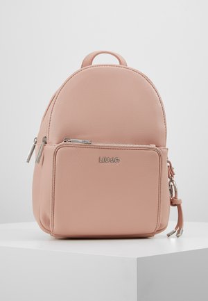 Pequeña mochila de color rosa pálido con bolsillo frontal con cremallera, tiradores de cremallera plateados y el logo de LIU JO en el bolsillo, descansando sobre una superficie blanca.