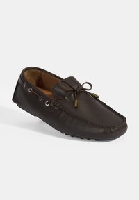 Donkerbruin leren mocassin schoen met een ronde neus, vetersluiting en decoratieve goudkleurige hardware. Geprofileerde buitenkant en een gladde binnenkant.