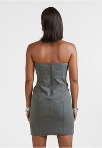 Sivá umelá kožená šaty bez ramienok s priliehavým strihom, vertikálnymi švami a zipsom na chrbte. Hladká textúra, dĺžka nad kolená.