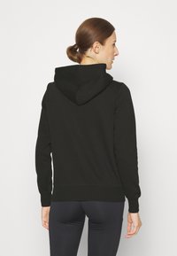 Felpa nera con cappuccio realizzata in tessuto morbido, caratterizzata da maniche lunghe, un orlo a coste e una vestibilità rilassata. Design semplice senza motivi visibili.