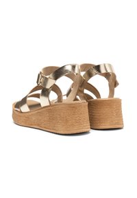 Metaliczne złote sandały na platformie z krzyżującymi się paskami, regulowanym zapięciem i teksturowanym, brązowym obcasem. Wykonane z gładkich i sztucznych materiałów skórzanych.