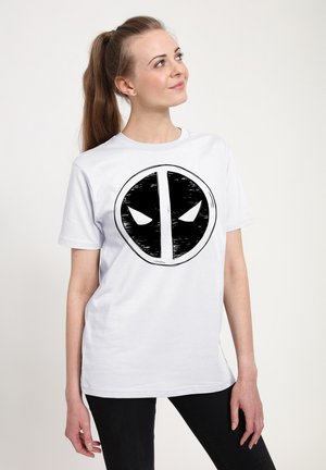 Hvid bomulds t-shirt med et stort sort-hvidt cirkulært grafisk motiv af et maskeret ansigt med stiliserede øjne, rund hals design.