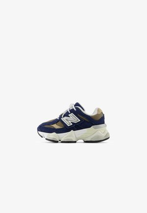 Baskets New Balance bleu marine et beige avec lacets blancs, tige en mesh et suède, et semelle blanche épaisse avec crampons noirs.