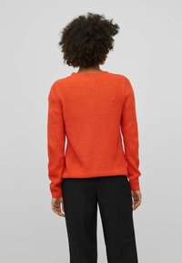 Orangener, gestrickter Pullover mit lockerer Passform, rundem Ausschnitt, gerippten Bündchen und Lochstrick-Details an den Ärmeln.