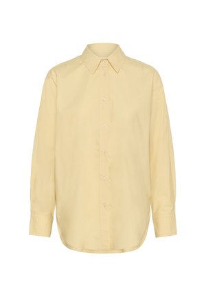 Chemise à manches longues jaune pâle à boutons, avec col pointu et poignets boutonnés, présentée sur un fond blanc.