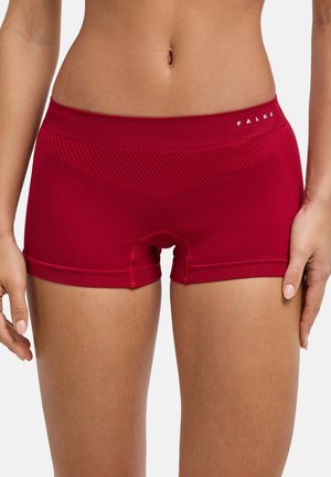 Vrouw die rode naadloze aansluitende shorts draagt met een getextureerd chevronpatroon en het "FALKE" logo op de tailleband, getoond van taille tot halverwege de dij.