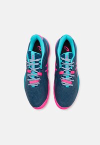 Scarpe sportive blu con accenti turchesi e suole rosa. Presentano una tomaia testurizzata e lacci a contrasto. Design leggero per prestazioni ottimali.