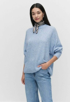 Hellblauer, gestrickter Pullover mit geripptem Saum und Bündchen, im lässigen Schnitt. Kombiniert mit hellen Denim-Jeans und einem gemusterten Seidenschal.