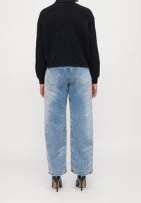 Czarny, dzianinowy sweter o krótkim kroju zestawiony z jasnoniebieskimi, szerokimi spodniami jeansowymi o wypranym wyglądzie denimu i subtelnych błyszczących akcentach.