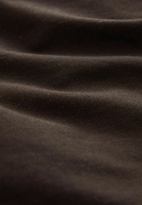 Dark brown fabric with a smooth, textured surface featuring subtle wrinkles and folds, highlighting its tactile quality and sheen.