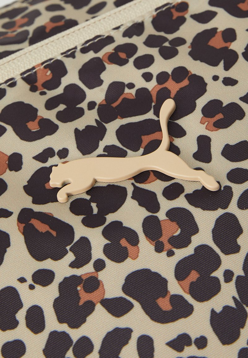 Puma-Tasche mit einem Leopardenmuster in Beige, Schwarz und Braun; zeichnet sich durch ein auffälliges beigefarbenes Logo-Element auf der Vorderseite aus.