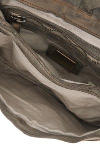 Interno della borsa in tessuto, con rivestimento in tessuto beige, tasca con zip e cuciture marroni. Palette di colori complessiva smorzata con dettagli di texture.