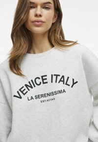 Siv gray pulover z črnim napisom "VENECIJA ITALIJA LA SERENISSIMA EST. 421PR." Mehka tkanina s dizajnom okroglega izreza.