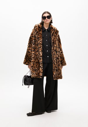 Abrigo de pelaje sintético con estampado de leopardo y un cuello ancho, combinado con una camisa negra de botones y pantalones de pierna ancha, complementado con un pequeño bolso negro.