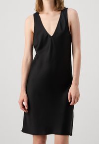 Schwarzes ärmelloses Kleid aus glattem Stoff, mit einem tiefen V-Ausschnitt und einer schlichten Silhouette. Der Saum ist am unteren Ende leicht geschwungen.