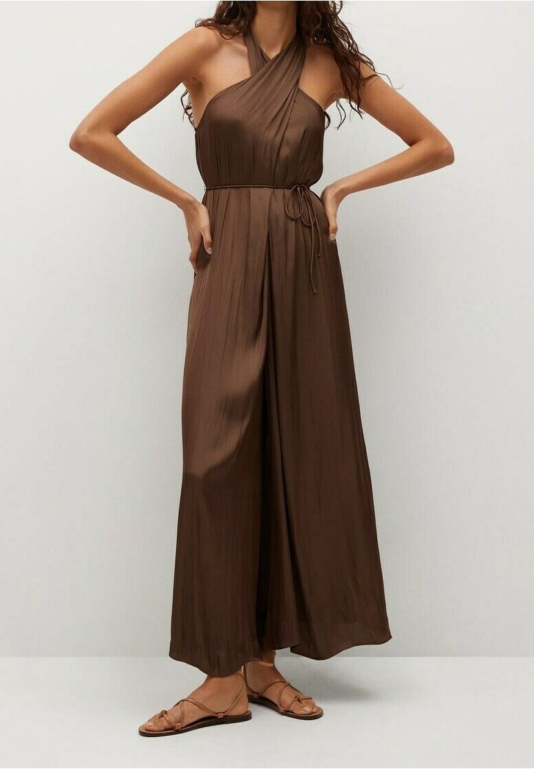 Mono sin mangas en color marrón con cuello halter, textura plisada y cintura atada. Combinado con sandalias planas con tiras.