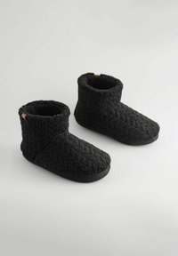 Fekete, bokáig érő papucsok, texturált kötött anyagból, gyémánt mintával, puha béléssel és gumitalppal.