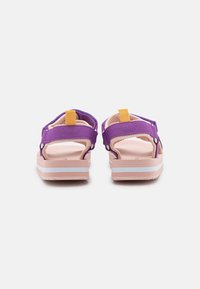 Violetti sandaalit säädettävillä remmeillä, vaaleanpunainen pohja ja valkoiset yksityiskohdat. Raketekstuuri ja kumimateriaali takaavat kestävyyden ja mukavuuden.