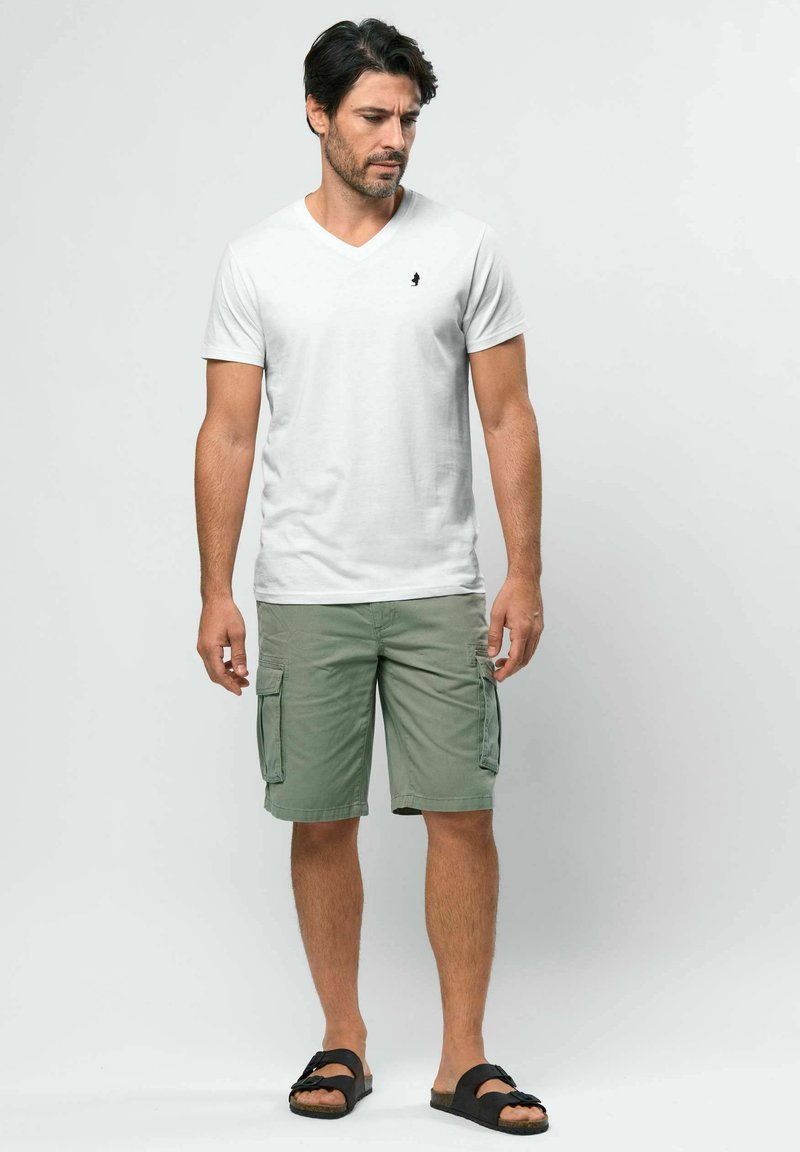 T-shirt blanc à col en V, short cargo kaki avec poches latérales, et sandales noires. Coupe décontractée, en coton, avec un détail de marque simple.