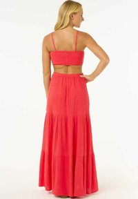 Koralfarvet sæt med crop-top med smock og tiered maxi nederdel. Lavet af tekstureret stof, har justerbare stropper og en flydende silhuet.