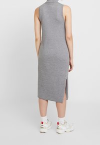 Ärml dress i ribbat grått med hög hals och sidospår, tillsammans med vita sneakers och ankelsockor. Enkelt, figurnära design.