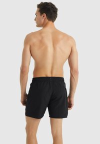 Pantaloni da nuoto neri con cintura elastica e tasche laterali, realizzati in un tessuto liscio e leggero, con un design semplice e monocolore.