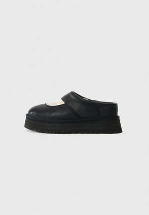 Sorte lær slip-on klodser med en forhøjet gummisål og en glat tekstur. Har en afrundet tå og en udskæringsdetalje på overdelen.