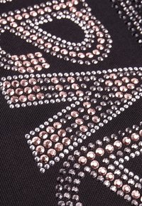 Tela negra con grandes piedras de rhinestone circulares en plata y oro rosa dispuestas en un patrón a través de la superficie.