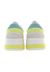 Vita och ljusgrå sneakers med turkosa och neon gula accenter, med en tjock vit sula och prägling med texten "SINCE 1890".