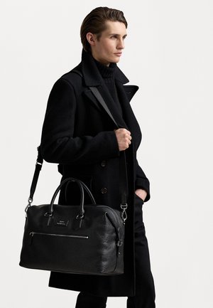 Musta nahkainen viikonloppulaukku yläkahvoilla ja irrotettavalla olkahihnalla. Karsittu pinta, etu-pikkupocket ja minimaalinen bränditys.