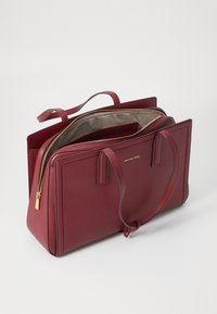 Rød læder tote taske med en struktureret design, dobbelt håndtag, hardware i guld tone og en dobbelt lynlås med en beige indvendig foret.
