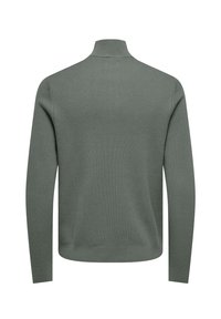 Suéter de cuello alto acanalado verde con mangas largas, un ligero cuello alto y un acabado texturizado. El diseño es clásico y ajustado.