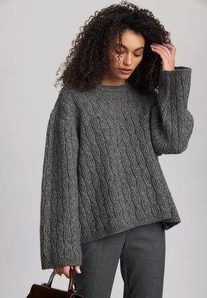 Grau gestrickter Pullover mit Rundhalsausschnitt, fallenden Schultern und langen Ärmeln. Lockere Passform mit einem strukturierten Muster und gerippten Abschlüssen.