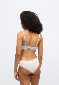 Lyseblå bh med justerbare stropper og lukning bagpå, kombineret med cremefarvede trusser med blomstret blonderkant langs kanterne.