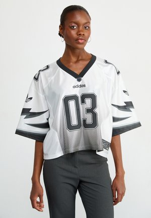 Biała siatkowa koszulka sportowa z czarnymi akcentami i numerem 03. Ma dekolt w kształcie litery V oraz krótki krój z dużymi rękawami. Zawiera logo Adidas.