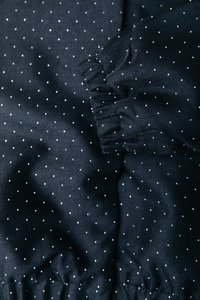 Tengerészkék anyag fehér pöttyökkel, ráncolt mandzsettákkal és sima textúrával, hangsúlyozva egy finom mintát és szerkezetet.