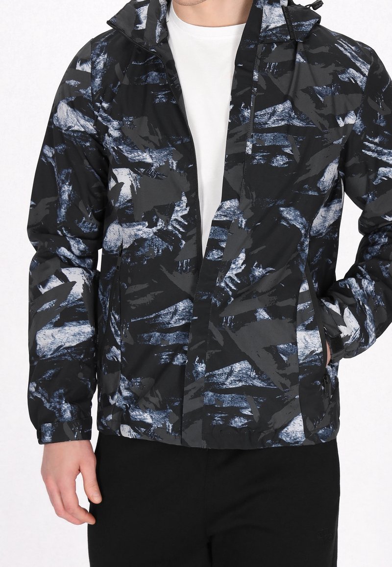 Veste légère à motifs noirs et bleus, dotée d'une fermeture éclair frontale, d'une capuche ajustable et de poches latérales. Tissu texturé avec des dessins abstraits.